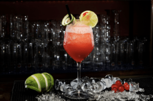 frozen strawberry daiquiri on bar surround by ice and limes